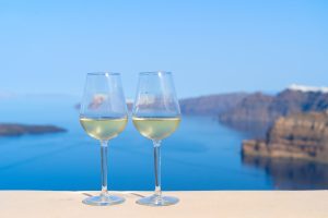 Two glasses of white wine with the Aegean sea behind, Greece