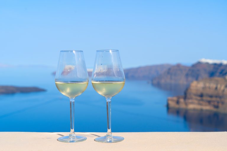Two glasses of white wine with the Aegean sea behind, Greece