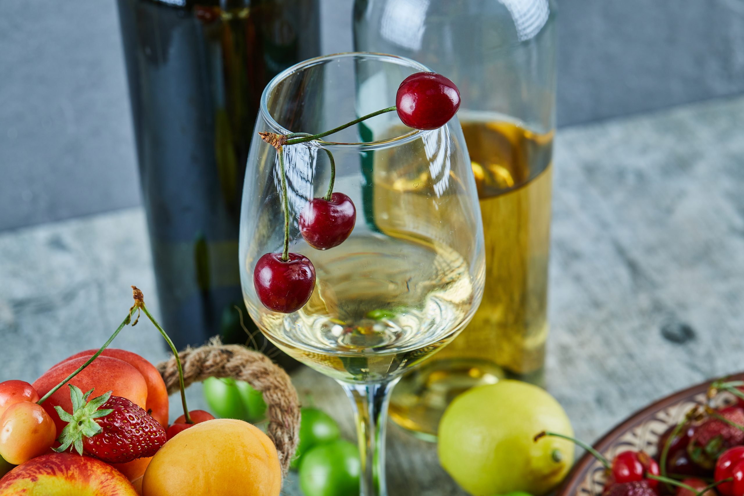 A glass of chilled white wine with summer fruit and lemon