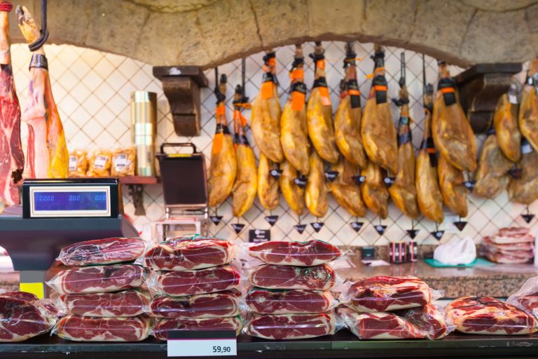 Hams and cured meats on a food market counter