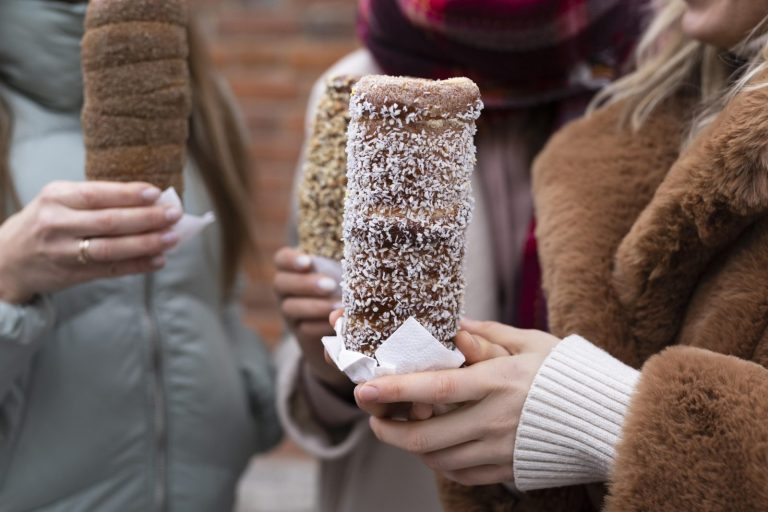 Hands holding Hungarian kurtoskalacs chimney cakes at a Christmas market