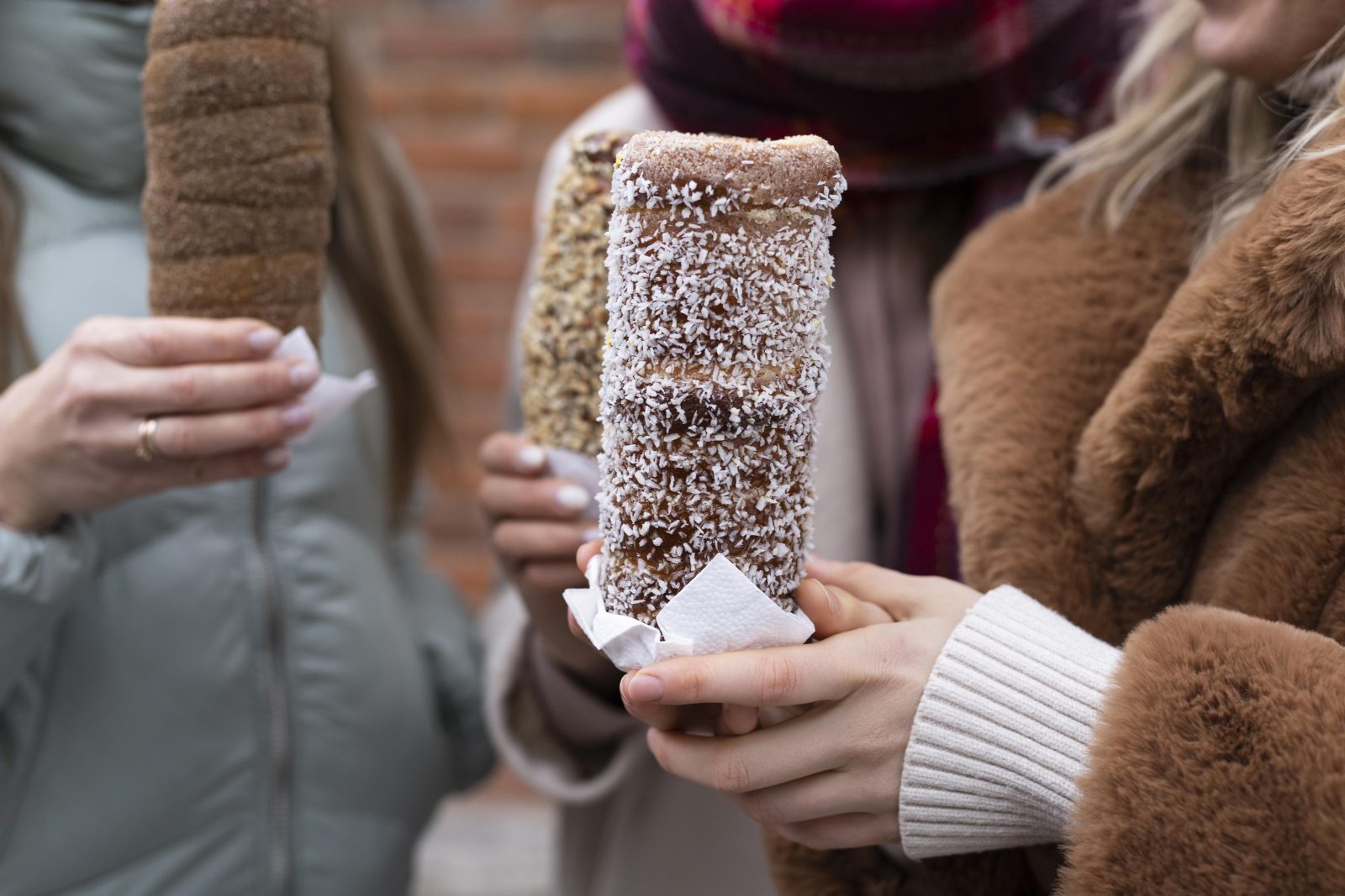 Hands holding Hungarian kurtoskalacs chimney cakes at a Christmas market