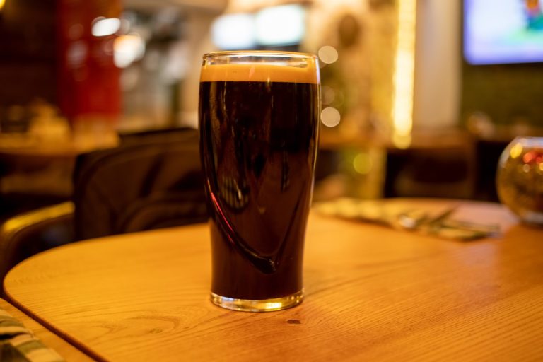 A pint of stout on a wooden pub table