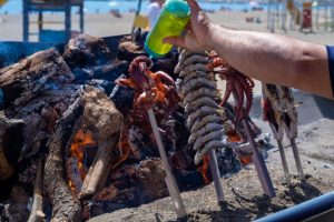 Espetos of sardines grilling on a Málaga beach
