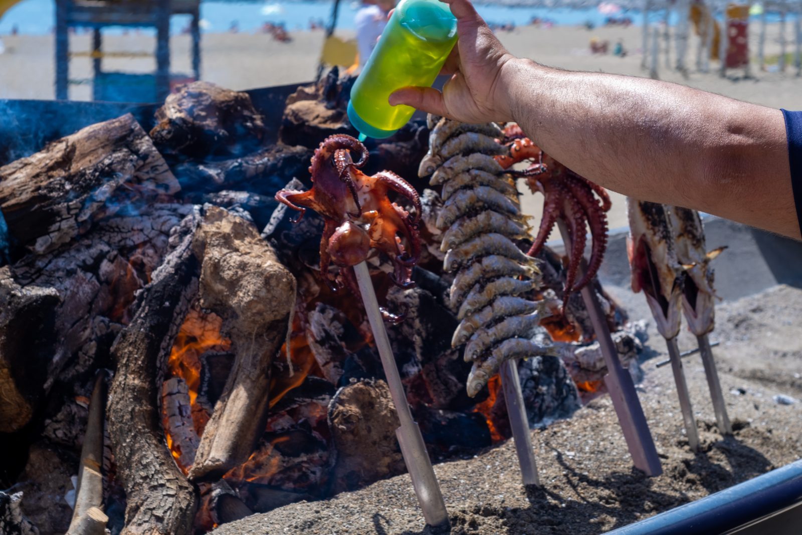 Espetos of sardines grilling on a Málaga beach